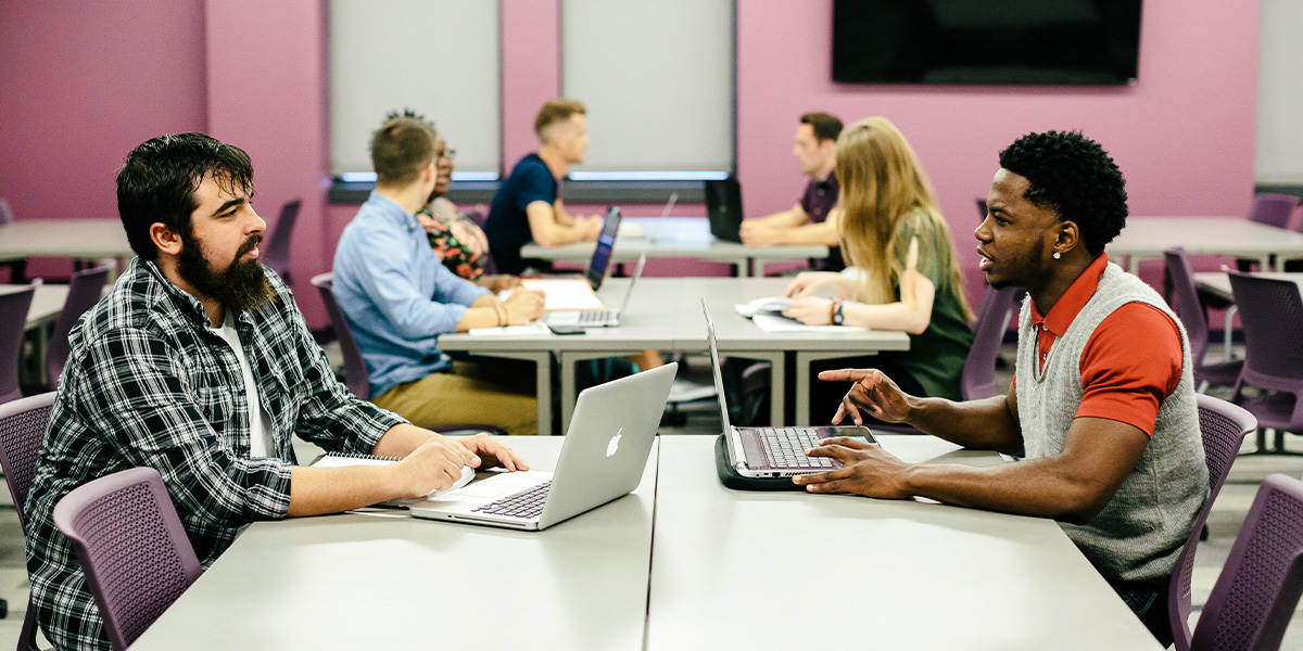 students smiling while sitting in desks in a in classroom